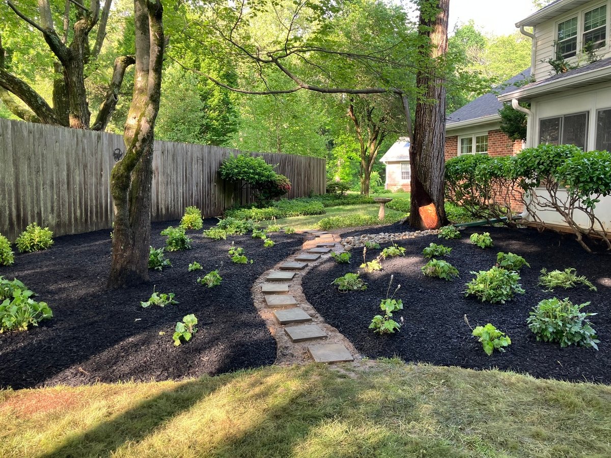 Beautiful landscaped garden with stone path and shade trees by First Class Lawncare, LLC in Wilmington, DE