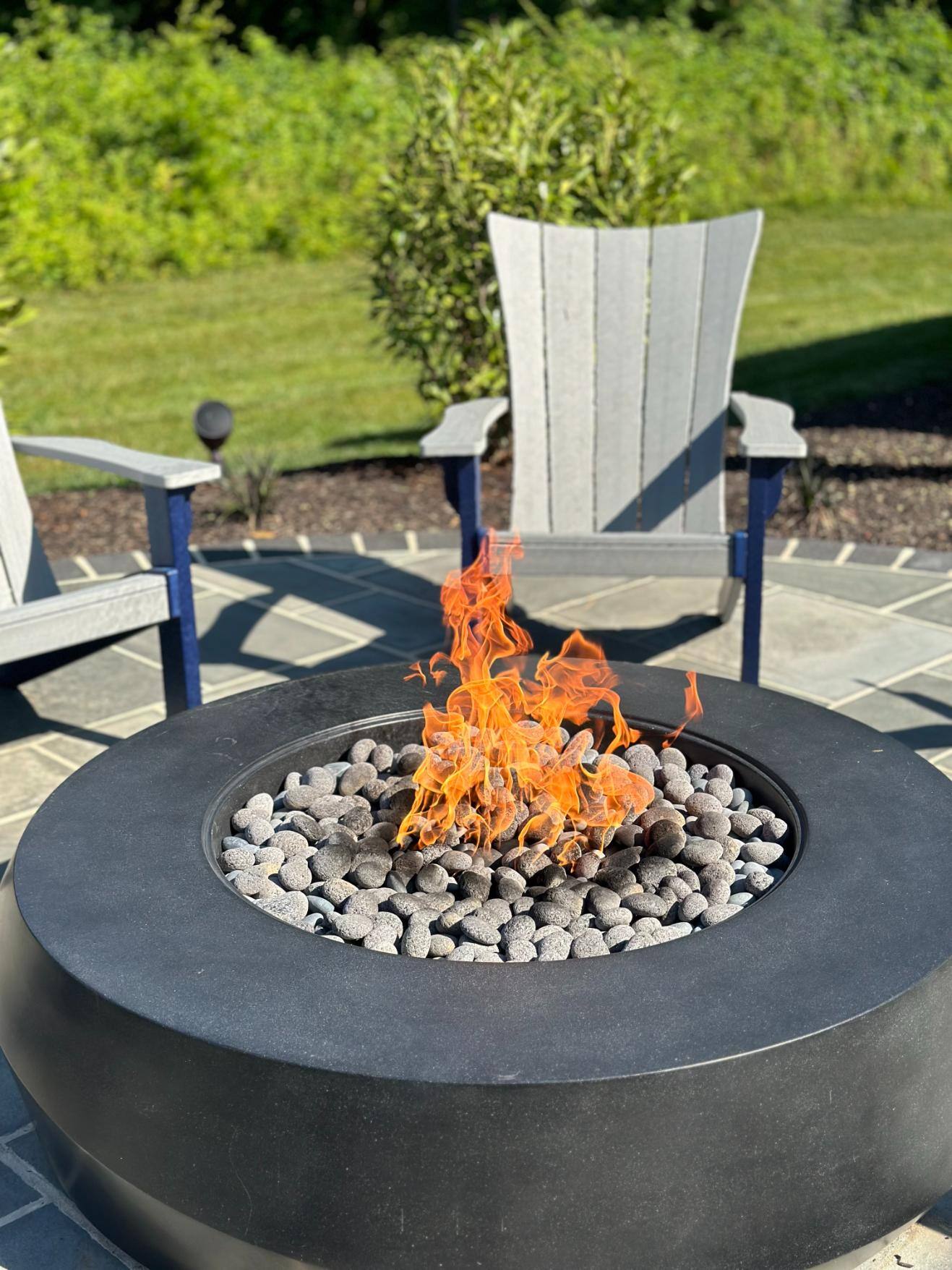 Close-up of firepit fire and patio chairs on patio hardscaping and landscaping by First Class Lawn Care in Wilmington, DE