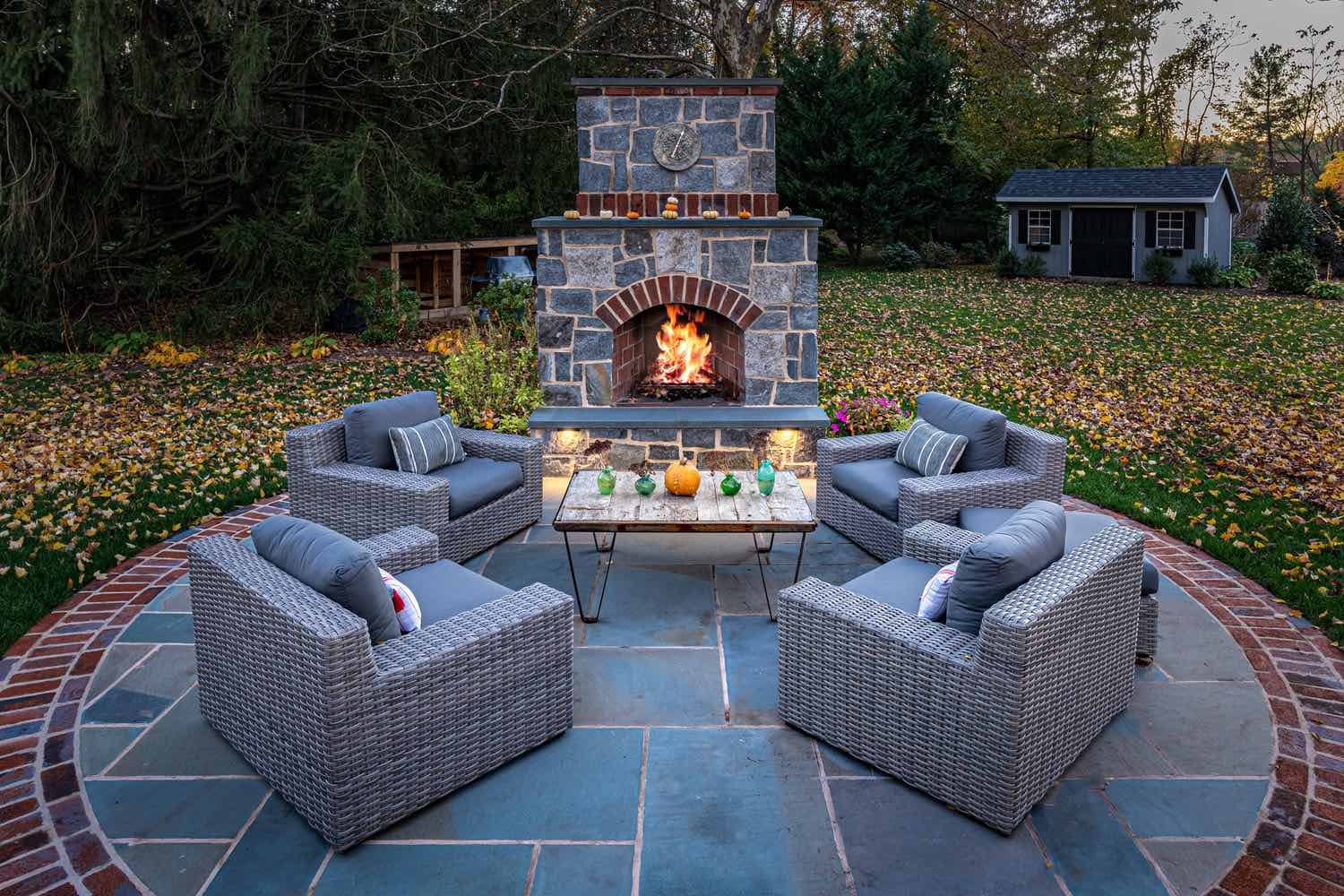 Custom Patio With Stone Fireplace and Surrounding Seating by First Class Lawn Care