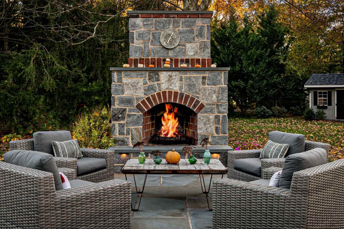 Outdoor Patio With Seating and Custom Stone Fireplace by First Class Lawn Care