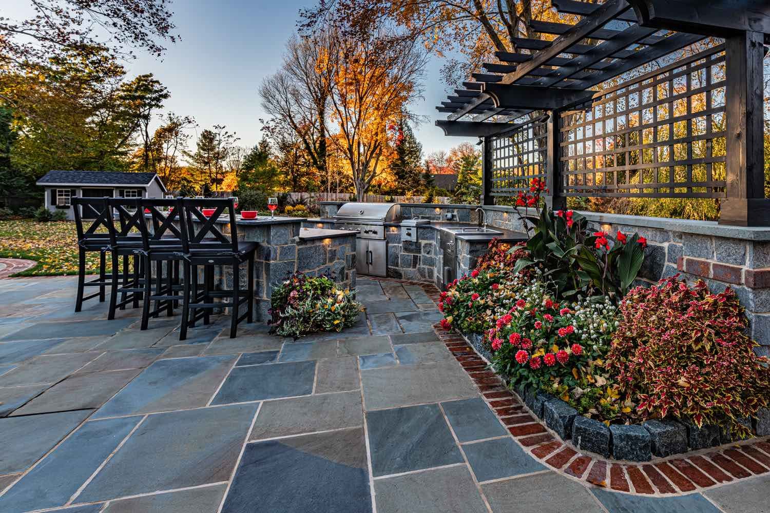 Patio With Outdoor Kitchen and Flowerbed by First Class Lawn Care 