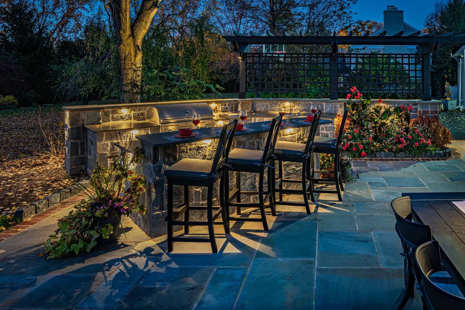 Outdoor Kitchen With Custom Island and Lighting by First Class Lawn Care