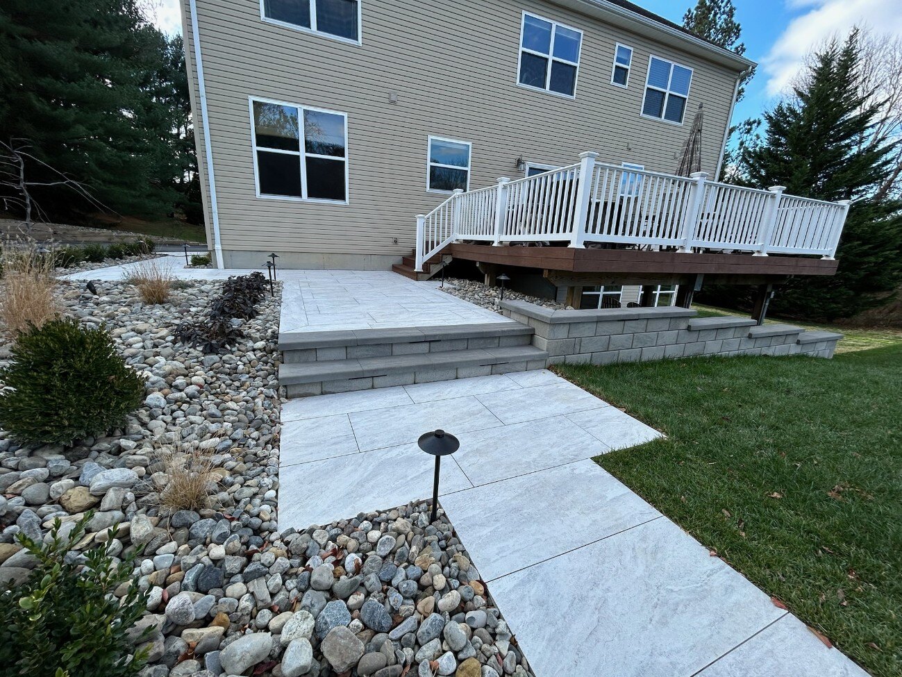 A beautifully designed hardscape featuring stone steps, a spacious porcelain patio, and a landscaped garden in Newark, DE by First Class Lawncare LLC