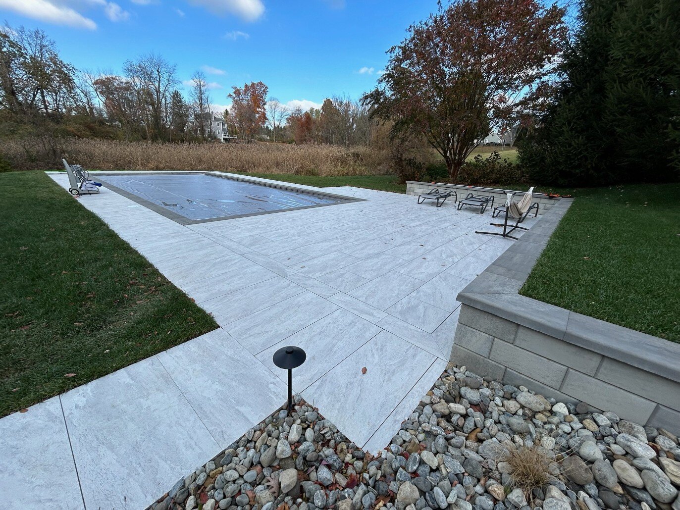 A custom backyard with a sleek porcelain patio and stylish lounge chairs in Newark, DE by First Class Lawncare LLC