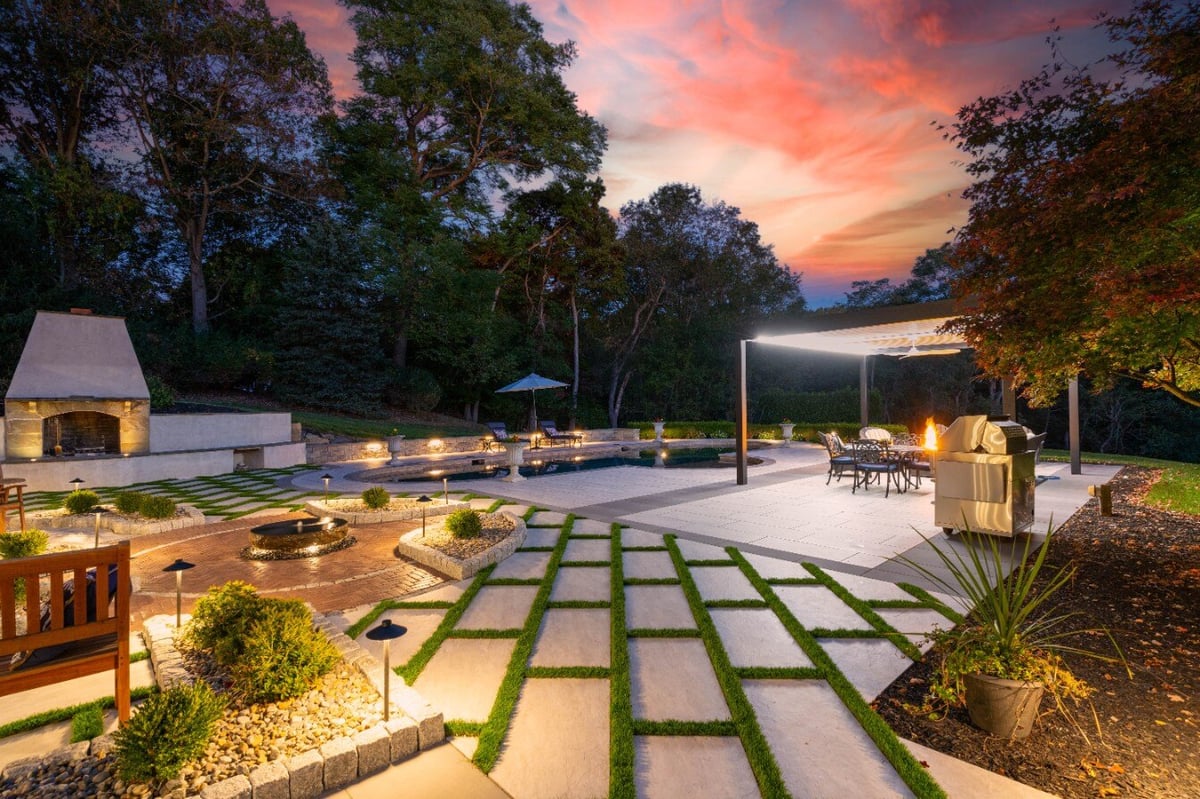 Beautifully lit patio with fire pit and modern hardscape design at sunset, hardscaping in West Chester, PA by First Class Lawn Care