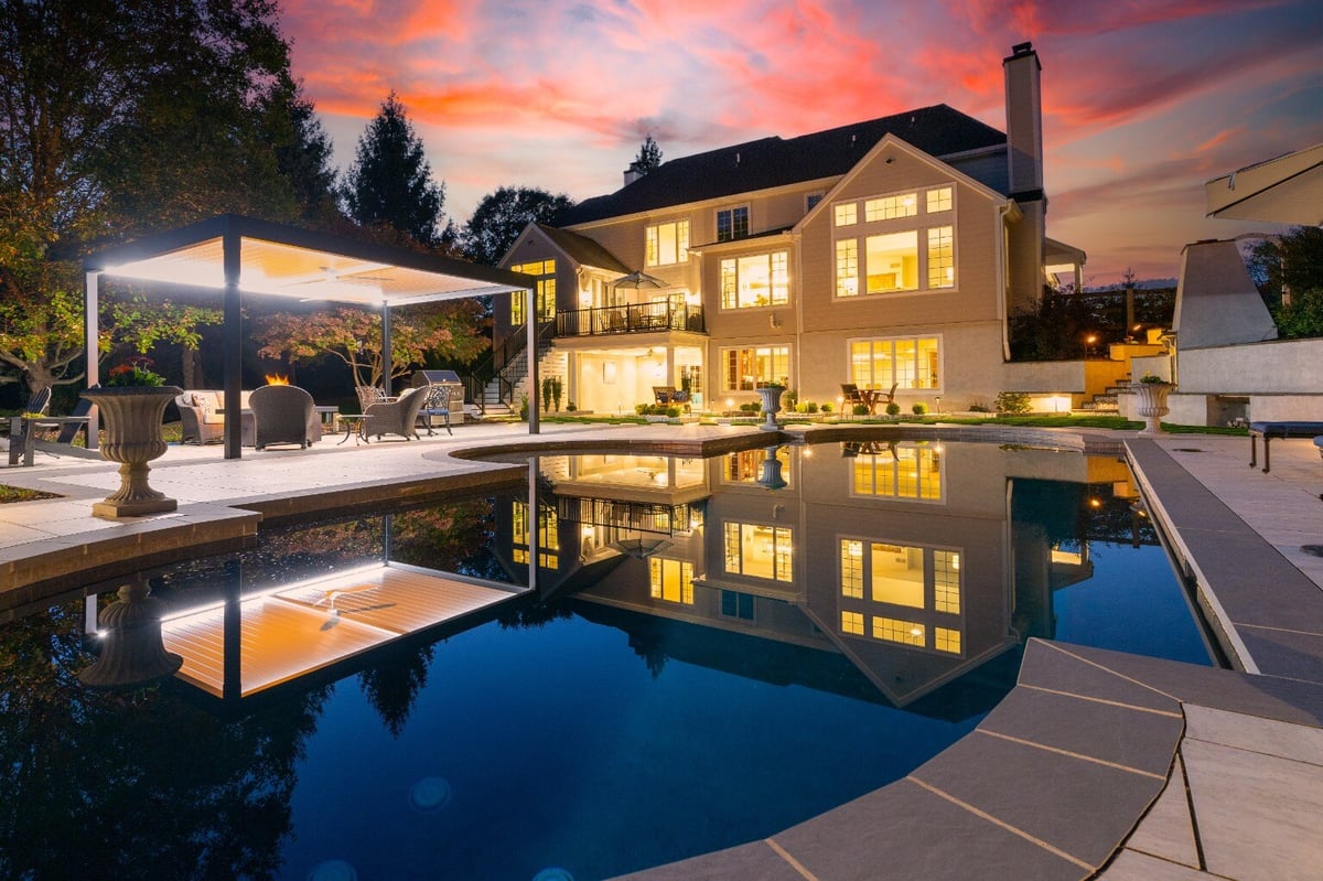 Evening view of a modern hardscape with poolside lighting and pergola, in West Chester, PA by First Class Lawn Care