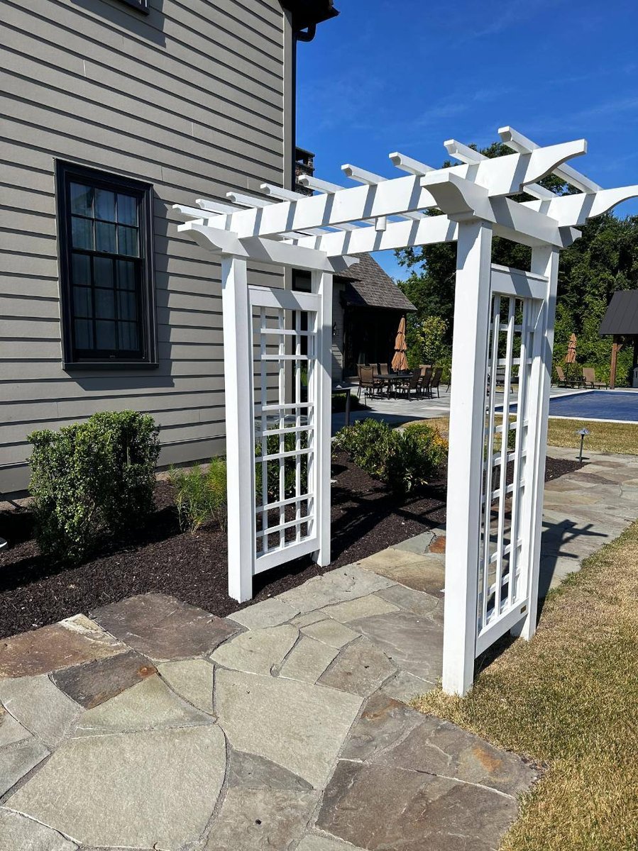 White pergola at patio entry by First Class Lawn Care in Wilmington, DE